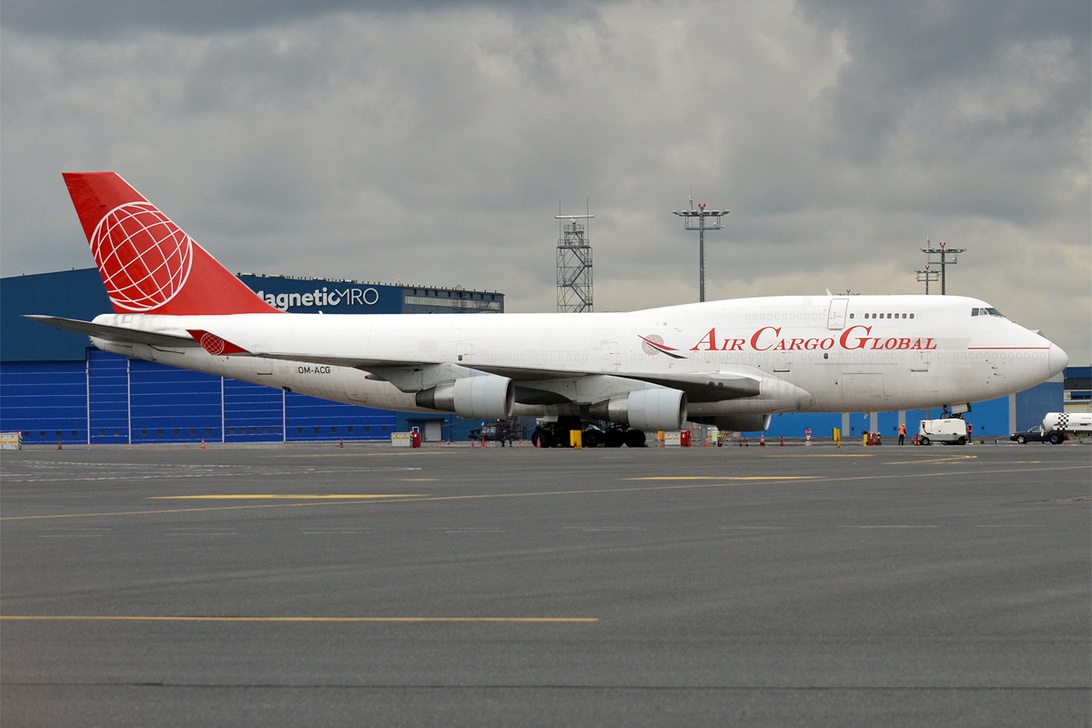 Ett stort fraktflygplan från AIR CARGO GLOBAL på en flygplats, omgiven av markutrustning.
